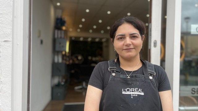 A woman in a L'Oreal apron stood outside a salon