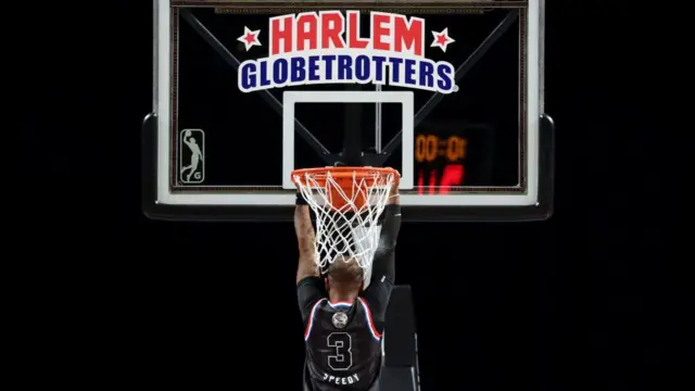 A Harlem Globetrotters player hangs off the basket during a performance last year