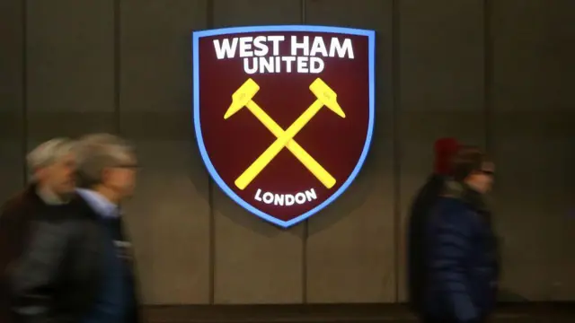 West Ham badge with people walking in front