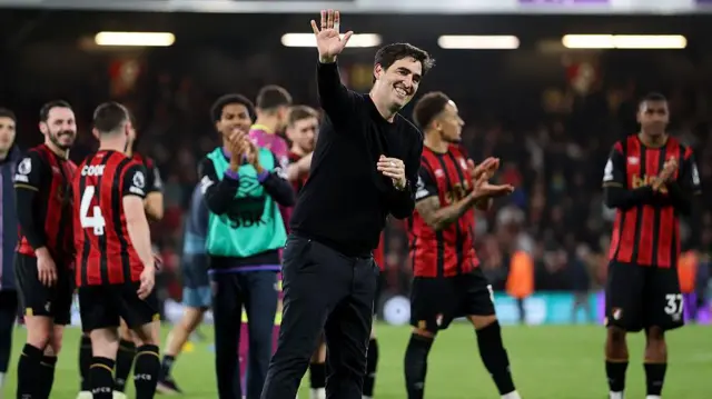 A smiling Andoni Iraola waves to the crowd with Bournemouth players behind him