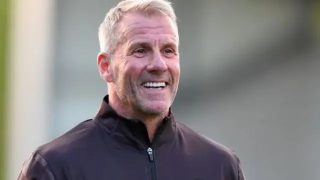 Mike Stowell holding a green and white football
