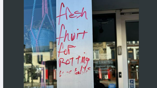 The outside of the cafe is daubed with graffiti in red writing saying "fresh fruit for rotting vegetables". 