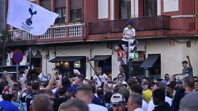 A large group of Tottenham fans gather in the street