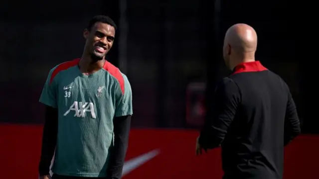 Ryan Gravenberch smiles as he speaks to Arne Slot in Liverpool training