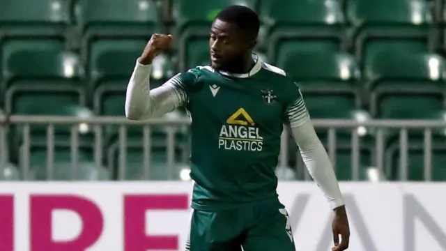 David Ajiboye celebrates a goal while playing for Sutton in green against Newport at Rodney Parade