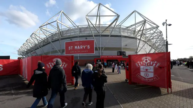 A photo of people walking towards St Mary's Stadium in Southampton with a big 'This is St Mary's' sign written across the stadium walls