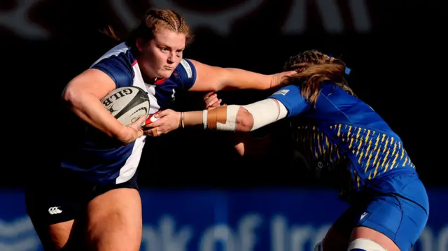 Sophie Barrett of the Wolfhounds hands off an opponent with the ball under one arm