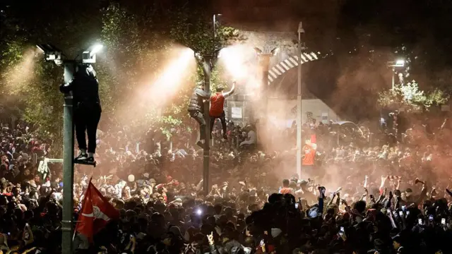 Arsenal fans climb lamp posts and celebrate at Emirates Stadium