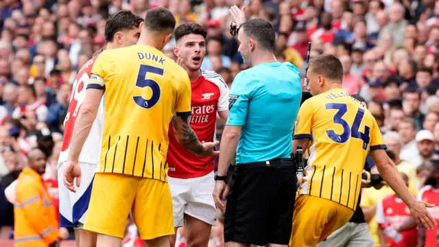 Arsenal and Brighton players surround the referee