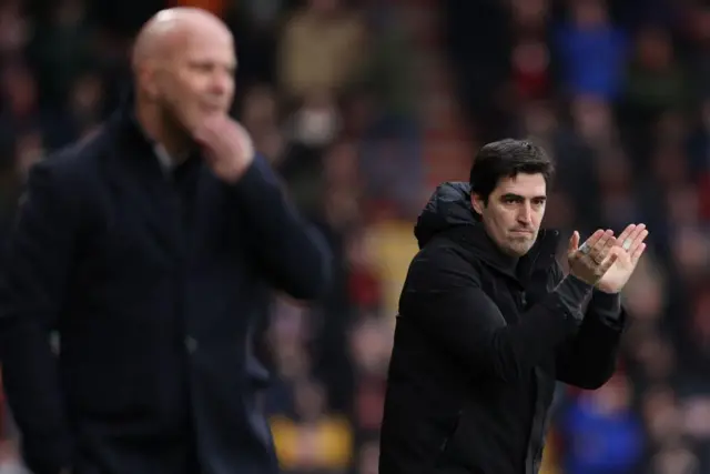 Andoni Iraola applauding his players on the touchline with Arne Slot out of focus in the foreground