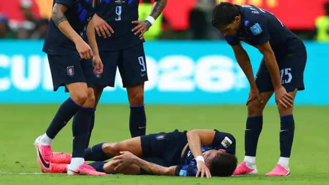 Manuel Ugarte holds injured knee on the floor while being looked at by team-mates
