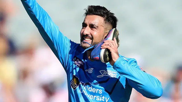 Tabraiz Shamsi celebrates by holding his shoe to his ear