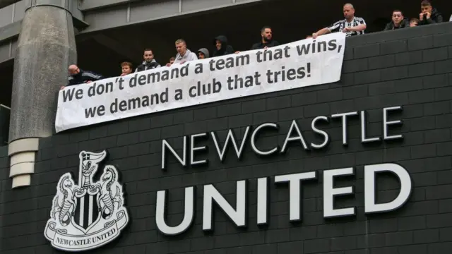 Newcastle fans with banner 'we don't demand a team that wins, we demand a club that tries'