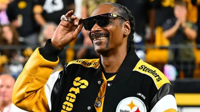 Snoop Dogg wearing a Pittsburgh Steelers jacket at one of the team's games