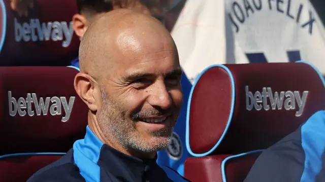 Chelsea's Italian head coach Enzo Maresca smiles in his seat ahead of kick-off in the English Premier League football match between West Ham United and Chelsea at the London Stadium