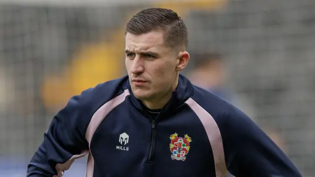 Aaron McGowan warms up before a match for Tranmere Rovers. He is wearing a navy blue sweat top with the club's badge.