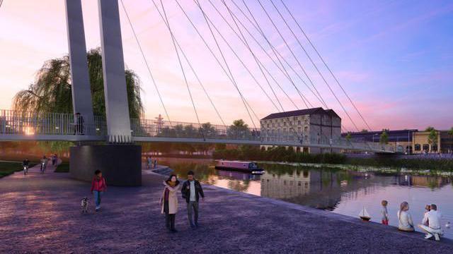 An artist's impression showing people walking near a bridge over a river. This view of the bridge is closer. The wires holding the bridge stretch down from above. People are walking on a wide footpath next to the river. A warehouse-style building can be seen on the other side of the river. A canal boat is going under the bridge.