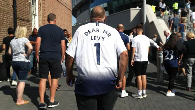 A Spurs fan with 'Dear Mr Levy 1' on the back of his shirt arrives at the Tottenham Hotspur Stadium