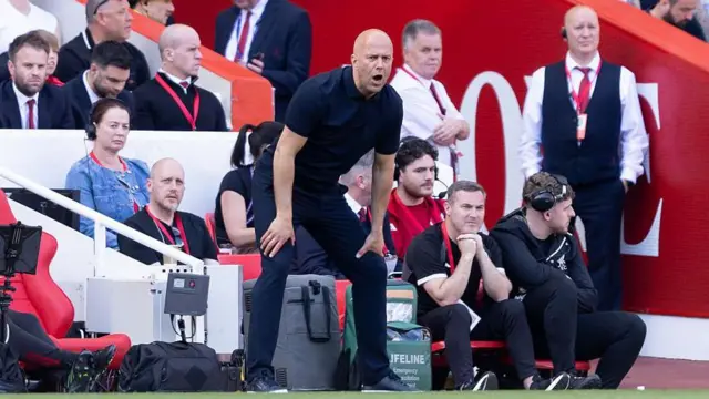 Arne Slot on the touchline at Anfield with his hands on his knees