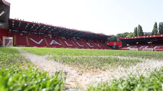 Shot of Charlton Athletic's Valley stadium empty, taken from ground level from a corner quadrant up at the red and white seats of the main stand