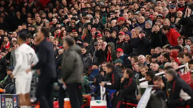 Fans look toward player and manager on the touchline