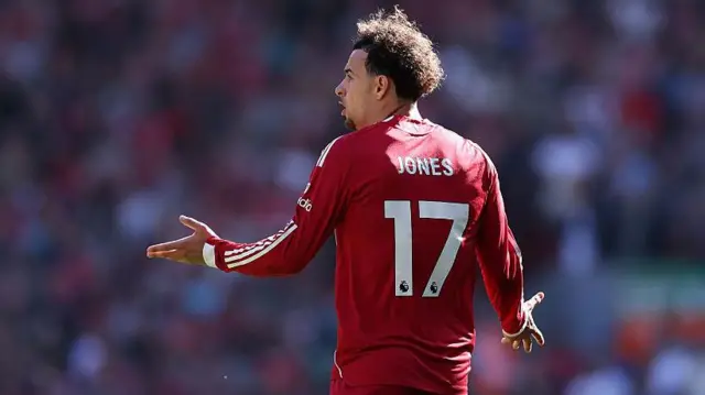 Curtis Jones playing for Liverpool, standing with his arms out in protest at a decision
