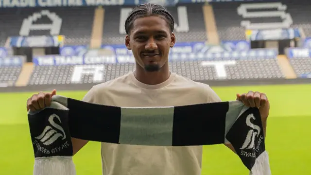 New Swansea City signing Staitham Bowen holding a club scarf in front of him at the Swansea.com Stadium 