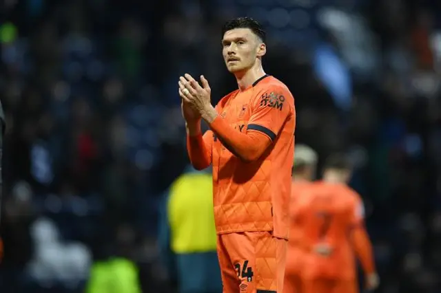 Kieffer Moore in an orange Ipswich away kit applauds fans