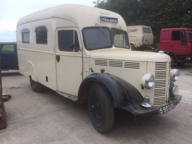 Cream-coloured wartime ambulance with a silver bell on the front.