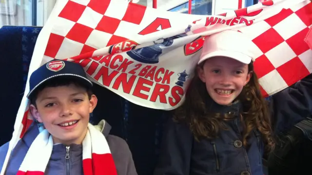 Two children pose with a red-and-white Arsenal flag