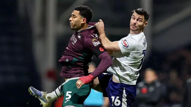 Swansea CIty's Ben Cabango jumps while Preston's Andrew Hughes behind him pulls his shirt. 