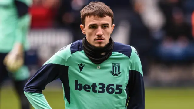 Nikola Jojic in a green Stoke City training top warms-up before a game at West Brom