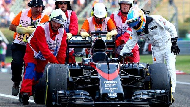 Fernando Alonso pushes his McLaren back to the pits with the aid of marshals