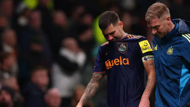 Bruno Guimaraes is assisted off the pitch by medical staff