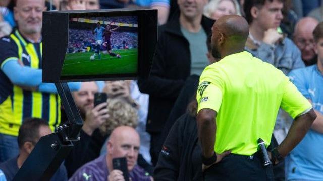 A referee looking at the pitchside monitor during a game