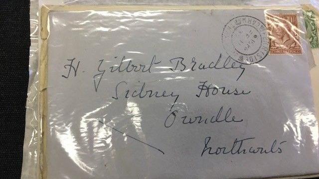 An envelope inside a plastic sleeve. It is addressed to Gilbert Bradley and has an old stamp on it