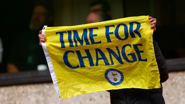A person holds up a Tottenham Time For Change flag