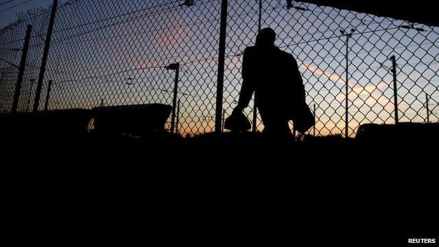 An African migrant walks after crossing a fence in an attempt to access the Channel Tunnel in Frethun, near Calais, France, August 8