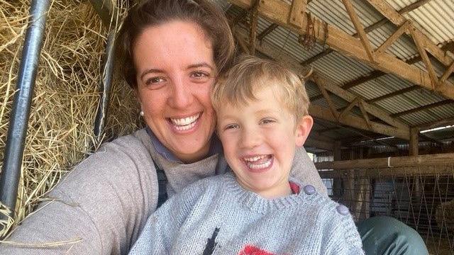 A selfie taken by mum Lucy who is smiling next to her young son Ollie, who has short blonde hair. They are sitting next to a hay bale in a barn