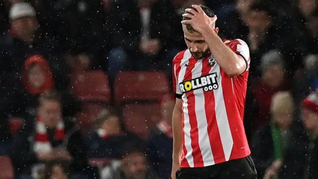 Jack Stephens leaves the pitch after being shown a red card