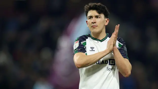 Luke O'Nien clapping towards the fans while wearing a Sunderland away shirt
