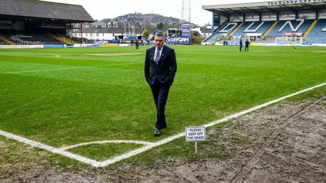 Tony Docherty walks on muddy Dens Park pitch