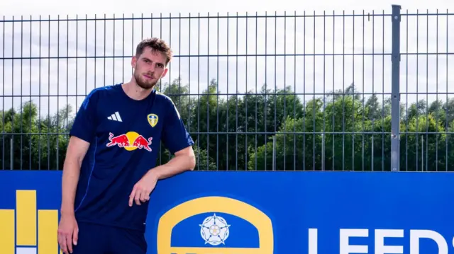 Anton Stach standing beside a Leeds United sign
