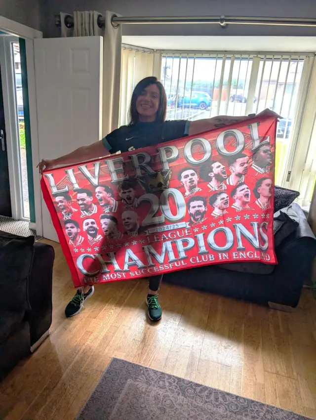 An image of a woman holding a Liverpool flag with 20th champions written on it
