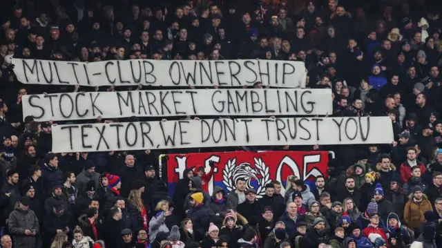 Crystal Palace fans protest with a banner reading "Multi-club ownership, stock market gambling, Textor, We don't trust you"