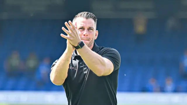 A photo of Matt Bloomfield applauding in a black polo shirt