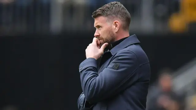 Rob Edwards standing on the touchline and holding his chin