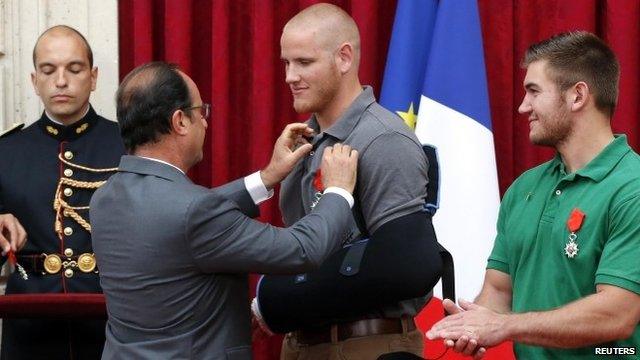 French President Francois Hollande (L) awards U.S. Airman First Class Spencer Stone (C) with the Legion d"Honneur (the Legion of Honour) medal as U.S. National Guardsman Alek Skarlatos applauds