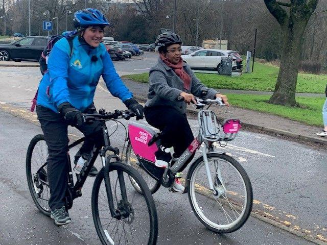 Nahla and her friend Carol Thompson ride along a cycle path at Kelvingrove park. Nahla rides a People Make Glasgow liveried hire bicycle.