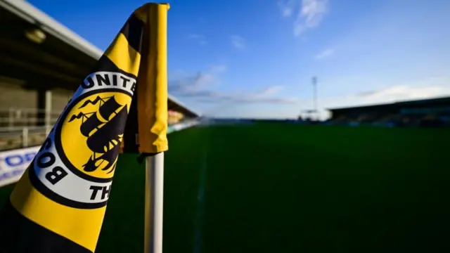The Boston United club badge is showing on the corner flag at the Jakemans Community Stadium which can be seen in the background.